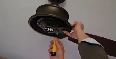 Electrician installing ceiling fan mounting bracket and fixture in Birmingham, AL