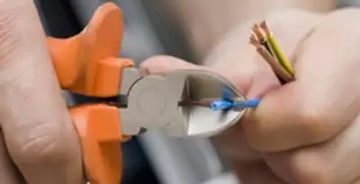 licensed electrician performing precise wire cutting and preparation during electrical service in Birmingham, AL