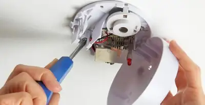 Certified technician wiring smoke detector during installation in Birmingham, AL